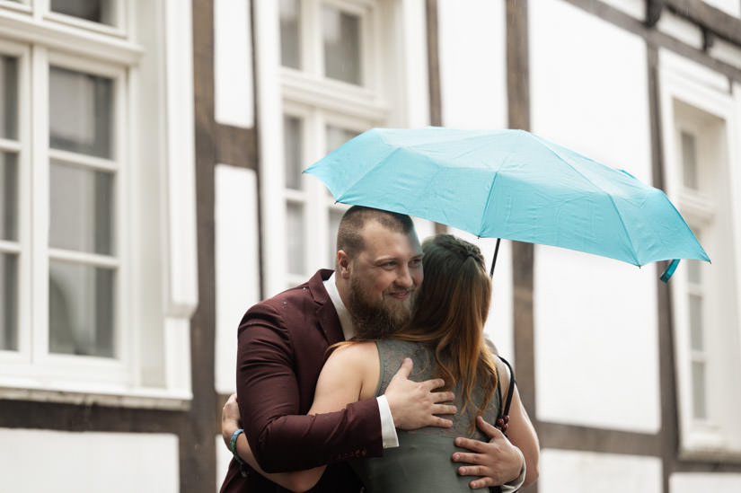 Bräutigam mit Gast unter blauem Regenschirm