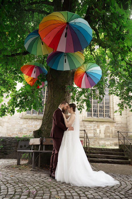 Brautpaar unter steht unter den bunten Regenschirmen vor dem Nicolaihaus