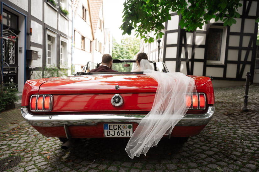 Brautpaar sitzt im roten Auto