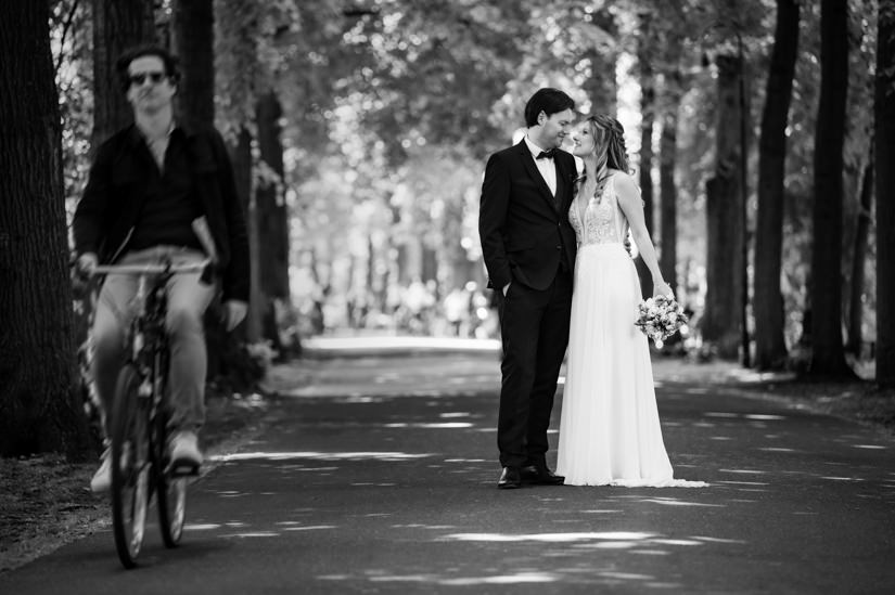 Hochzeitspaar auf der Promenade in Münster mit einem Fahradfahrer