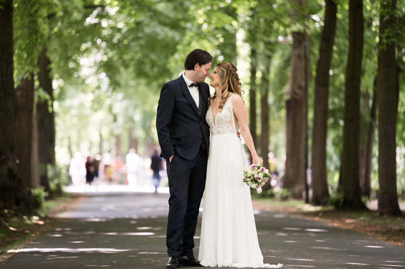 Das Hochzeitspaar steht Kopf an Kopf auf der Promenade in Münster